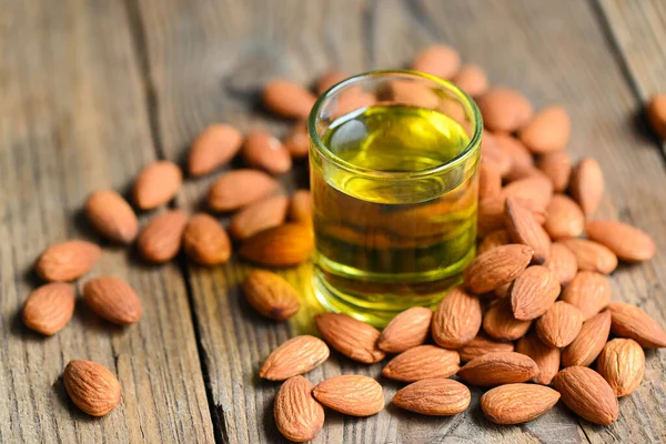 Almond oil and Almonds nuts on wooden, Delicious sweet almonds oil in glass, roasted almond nut for healthy food and snack organic vegetable oils for cooking or spa concept