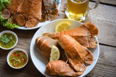 Fresh slipper lobster flathead boiled cooking with parsley rosemary in the restaurant, Flathead lobster shrimps served on white plate seafood sauce and mug beer glass, Rock Lobster Moreton Bay Bug