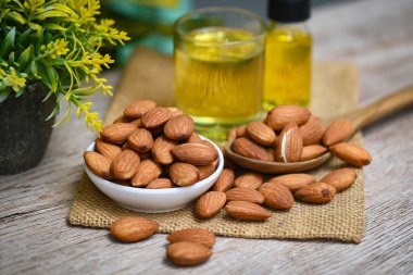 Almond oil and Almonds nuts on wooden, Delicious sweet almonds oil in glass, roasted almond nut for healthy food and snack organic vegetable oils for cooking or spa concept