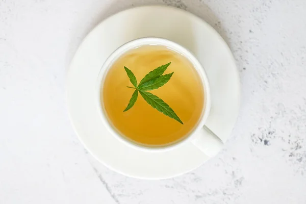 Cannabis tea herbal on tea cup with cannabis leaf marijuana leaves herb, health tea with hemp leaf plant THC CBD herbs food and medical - top view