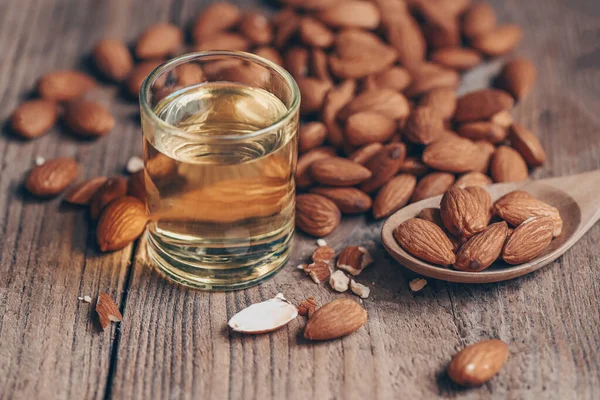 Almond oil and Almonds nuts on wooden, Delicious sweet almonds oil in glass, roasted almond nut for healthy food and snack organic vegetable oils for cooking or spa concept