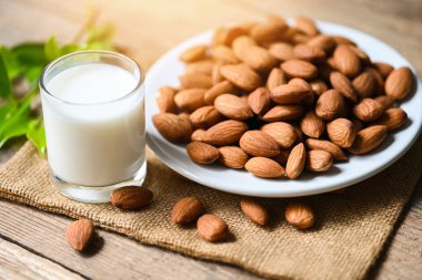 Almond milk and Almonds nuts on white plate background, Delicious sweet almonds on wooden table, roasted almond nut for healthy food and snack