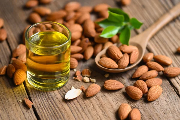 Almond oil and Almonds nuts on wooden, Delicious sweet almonds oil in glass, roasted almond nut for healthy food and snack organic vegetable oils for cooking or spa concept