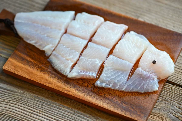 fish fillet on wooden board with ingredients for cooking, meat dolly fish tilapia striped catfish, fresh raw pangasius fish fillet - top view