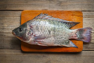 Tahta kesim tahtasında Tilapia, Tilapia çiftliğinden taze çiğ tilapia balığı.