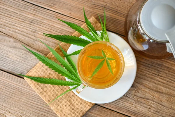 Cannabis tea herbal on tea cup with cannabis leaf marijuana leaves herb, Health tea with hemp leaf plant THC CBD herbs food and medical - top view