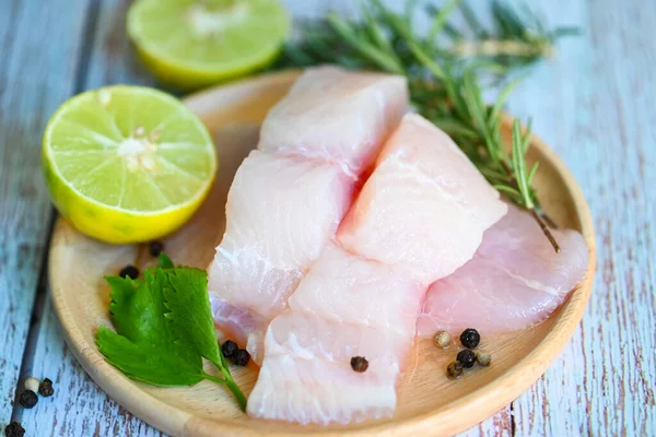 Fish fillet on wooden plate with ingredients celery for cookin, fresh raw pangasius fish fillet with lemon lime, meat dolly fish tilapia striped catfish - top view