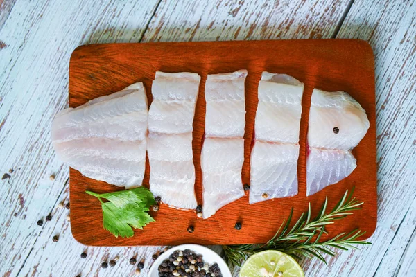 Fish fillet on wooden board with ingredients celery for cooking, fresh raw pangasius fish fillet with, meat dolly fish tilapia striped catfish - top view