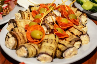 Patlıcan rulosu ve zeytinli sosis, bir tabağa yayılmış.