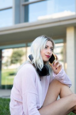 Üniversitede akıllı telefon kullanan güzel sarışın bir bayan öğrenci.