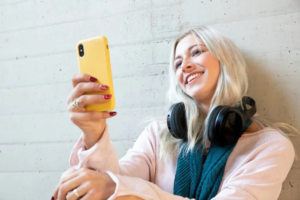 Üniversitede akıllı telefon kullanan güzel sarışın bir bayan öğrenci.