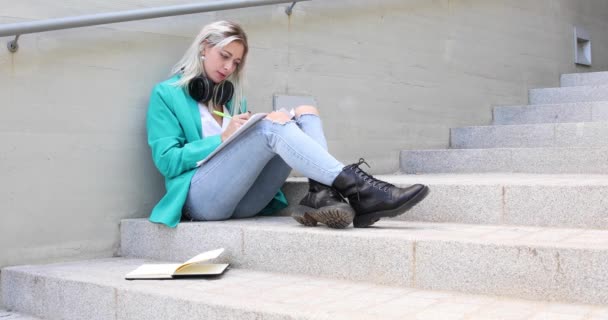 Молода блондинка університет студентка читає і вивчає на відкритому повітрі — стокове відео
