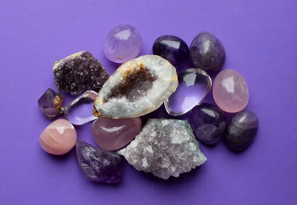 Beautiful gemstones,  geode amethyst and druses of natural purple mineral amethyst on a purple background. Amethysts and rose quartz. Large crystals of semi-precious stones.