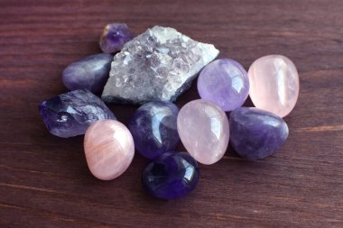 Güzel değerli taşlar, jeot ametist ve ahşap arka planda bulunan doğal mor mineral ametistleri. Ametist ve gül kuvars. Yarı değerli taşların büyük kristalleri..
