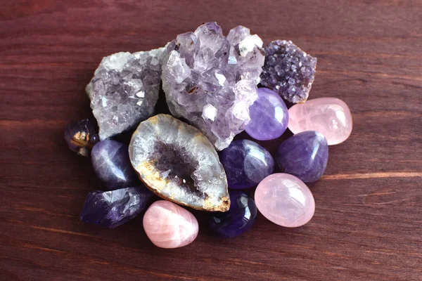 Beautiful gemstones,  geode amethyst and druses of natural purple mineral amethyst on a wooden background. Amethysts and rose quartz. Large crystals of semi-precious stones.