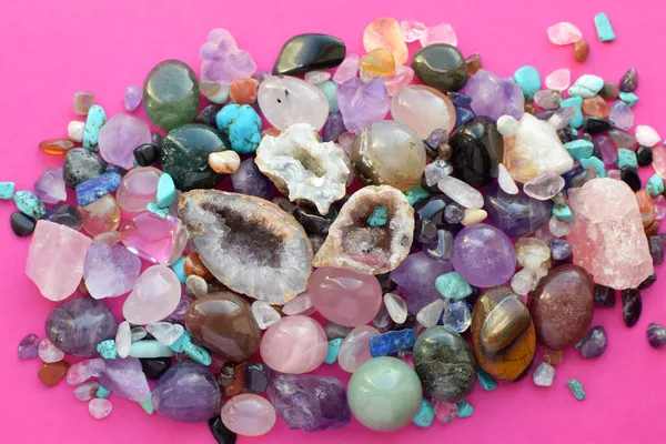 Gems of different colors. Amethyst, rose quartz, agate, apatite, aventurine, olivine, turquoise, aquamarine, rhinestone lie on a pink background