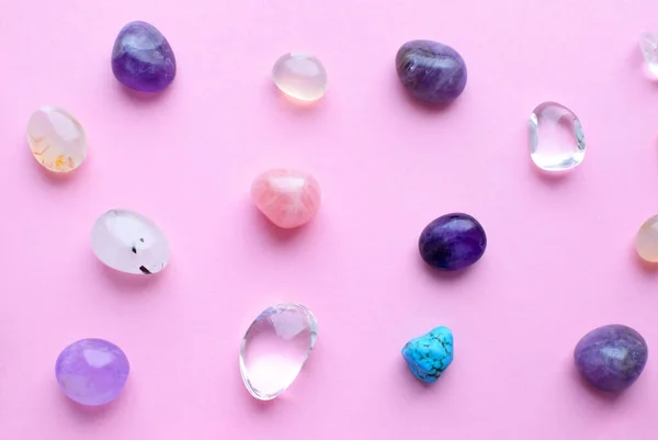 Gems of different colors. Amethyst, rose quartz, agate, apatite, aventurine, olivine, turquoise, aquamarine, rhinestone lie on a pink background. Flat la