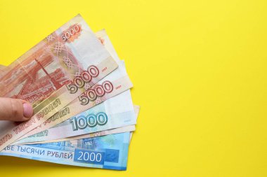 Rus rublesi banknotları sarı arka planda bir kadın elinde. Boşluğu kopyala.