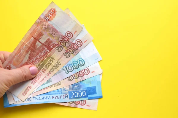 Rus rublesi banknotları sarı arka planda bir kadın elinde. Boşluğu kopyala.