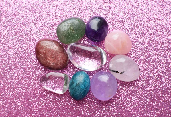 Gemstone minerals on a pink background. Round tumbling minerals of amethyst, rose quartz, apatite, turquoise, agate