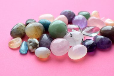 Farklı renkte mücevherler. Amethyst, rose quartz, agate, apatite, aventurine, olivine, turkuaz, aquamarine, pembemsi arka planda bulunan yapay elmaslar.