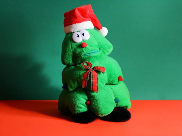 Gyerekek karácsonyi játék formájában egy karácsonyfa piros sapkában egy szomorú arcát. karácsonyi ajándék egy gyermeknek — Stock Fotó