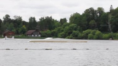 A man in a helmet rides a wakeboard in a wake park. jumping over obstacles on the water. active sports