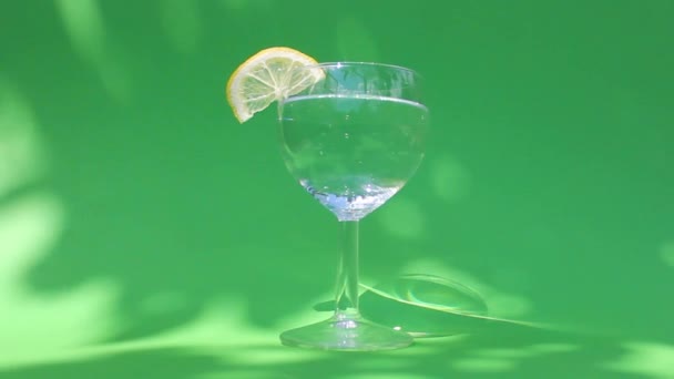 Стакан освежающей холодной воды с ломтиком лимона. концепция приготовления летних коктейлей — стоковое видео