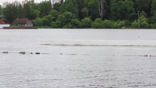 A man in a helmet rides a wakeboard in a wake park. jumping over obstacles on the water. active sports — 图库视频影像