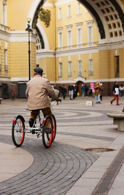 Rusya, Saint Petersburg 12 Ekim 2021. St. Petersburg şehrinin ana saray meydanının önünde üç tekerlekli bisiklete binmiş bir adam. Genelkurmay Başkanı..