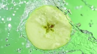 Dönen Yeşil Elma Dilimi ve Sulama Suyu 'nun Süper Yavaş Çekimi. 4K 'da yüksek hızlı sinema kamerası ile çekildi...