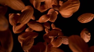 Black on Black 'in arkasındaki kameradan düşen taze bademlerin süper yavaş çekim sahnesi. Yüksek hızlı sinema kamerasıyla çekildi, 4K.