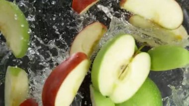 Kırmızı ve Yeşil Elma Kesikleri 'nin Süper Yavaş Çekimi. Düşüyor ve Suyun içine düşüyor. 4K 'da Yüksek Hız Sinema Kamerası ile çekildi..