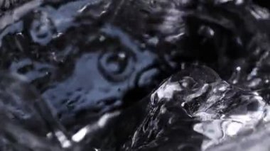 Super Slow Motion Makro Şat Ice Cube 'un Karanlık Arkaplanda Votka ile 1000 fps' te Cama Düşüşü. 4K Çözünürlükte Yüksek Hız Sinema Kamerası ile Çekim.