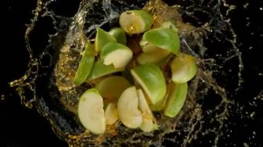 Patlayan yeşil elma kesiklerinin ve siyaha 1000 fitte sıçrayan sıvının süper yavaş çekimi. Yüksek hızlı sinema kamerasıyla çekilmiş..