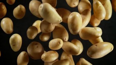 Süper Yavaş Sinema Çekimi. Taze Patatesler Siyah Arkaplan 'da kameraya doğru uçuyor. Yüksek hızlı sinema kamerasıyla çekildi, 4K.