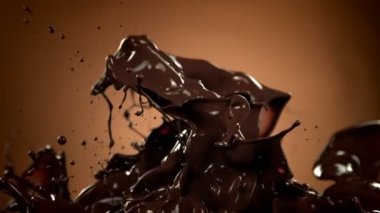 Kahverengi Gradyan Arkaplanda 1000 fps 'de Süper Yavaş Su Sıçratma Çekimi Eritilmiş Çikolata. 4K Çözünürlükte Yüksek Hız Sinema Kamerası ile Çekim.