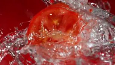 Süper Yavaş Domates Dilimleme ve Sıçratma Suyu Döndürme Çekimi 1000fps Kırmızı 'da izole edildi. 4K 'da yüksek hızlı sinema kamerası ile çekildi...