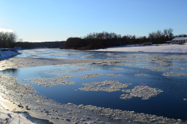 Mavi gökyüzünün arka planında buzla kaplı bir nehir.