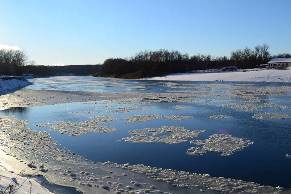 Mavi gökyüzünün arka planında buzla kaplı bir nehir.