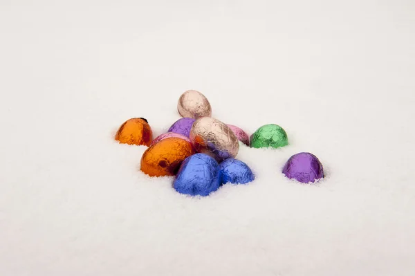 Colored chocolate Easter eggs in a snowy white background — Stock Photo, Image