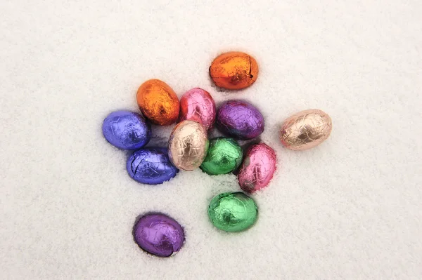 Colored chocolate Easter eggs in a snowy white background — Stock Photo, Image