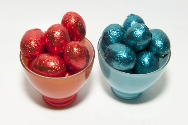 Colored chocolate Easter eggs in glass cups of the same color — Stock Photo, Image