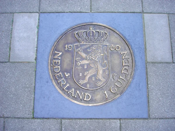 Coin of one guilder in pavement — Stock Photo, Image