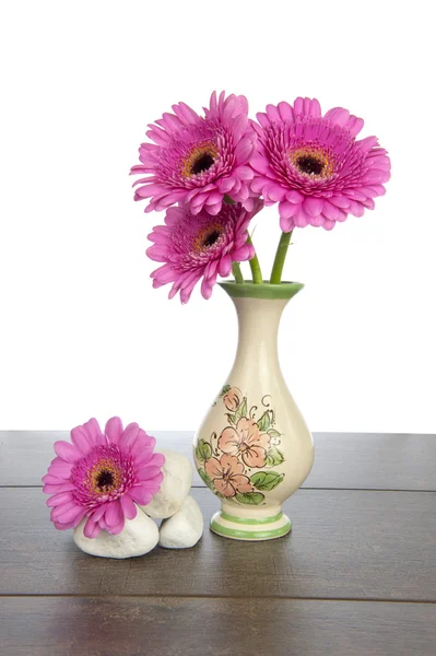 Gerberas rosadas en jarrón decorado y rocas blancas —  Fotos de Stock