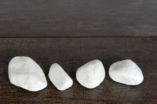Four white rocks on brown wood — Stock Photo, Image