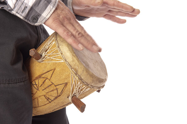 Человек, играющий на африканском барабане между ног
