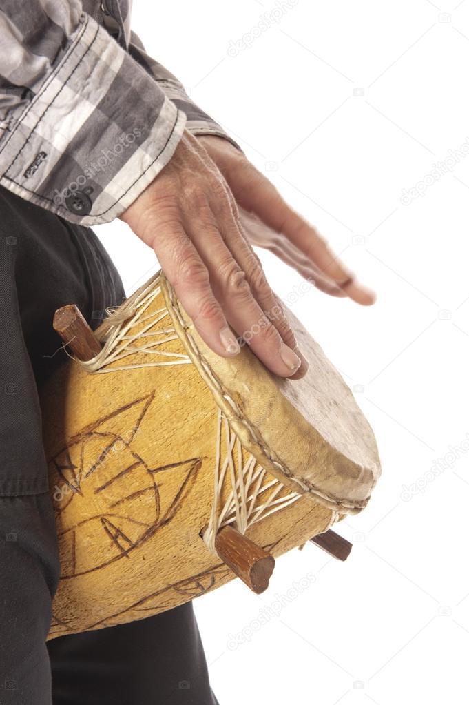 Male playing African drum between legs