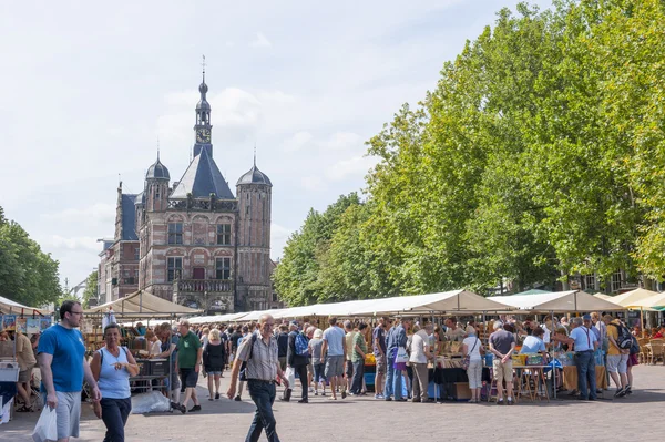 De deventer boekenmarkt in Nederland op augustus 3, 2014. "de rand" plaza vol met mensen met de beroemde en historische gebouw "de waag" op de achtergrond. — Stockfoto
