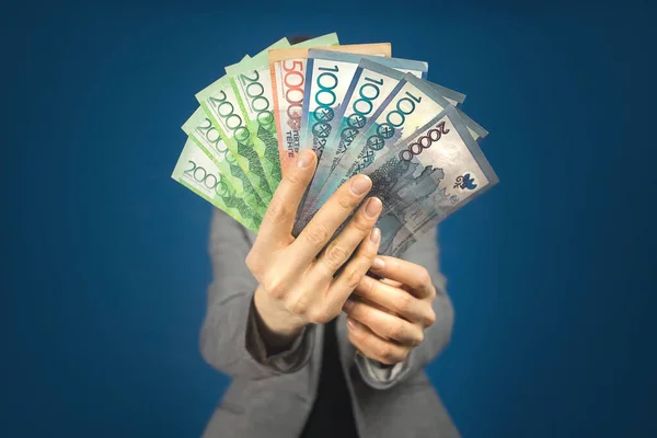 Kazakistan 'da çeşitli mezhepler var. Gri ceketli bir kadının arka planına karşı para ellerinde..